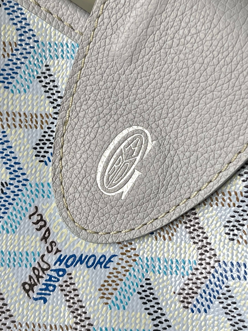 Light blue and white patterned fabric with gray circular emblem patch on corner