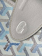 Light blue and white patterned fabric with gray circular emblem patch on corner