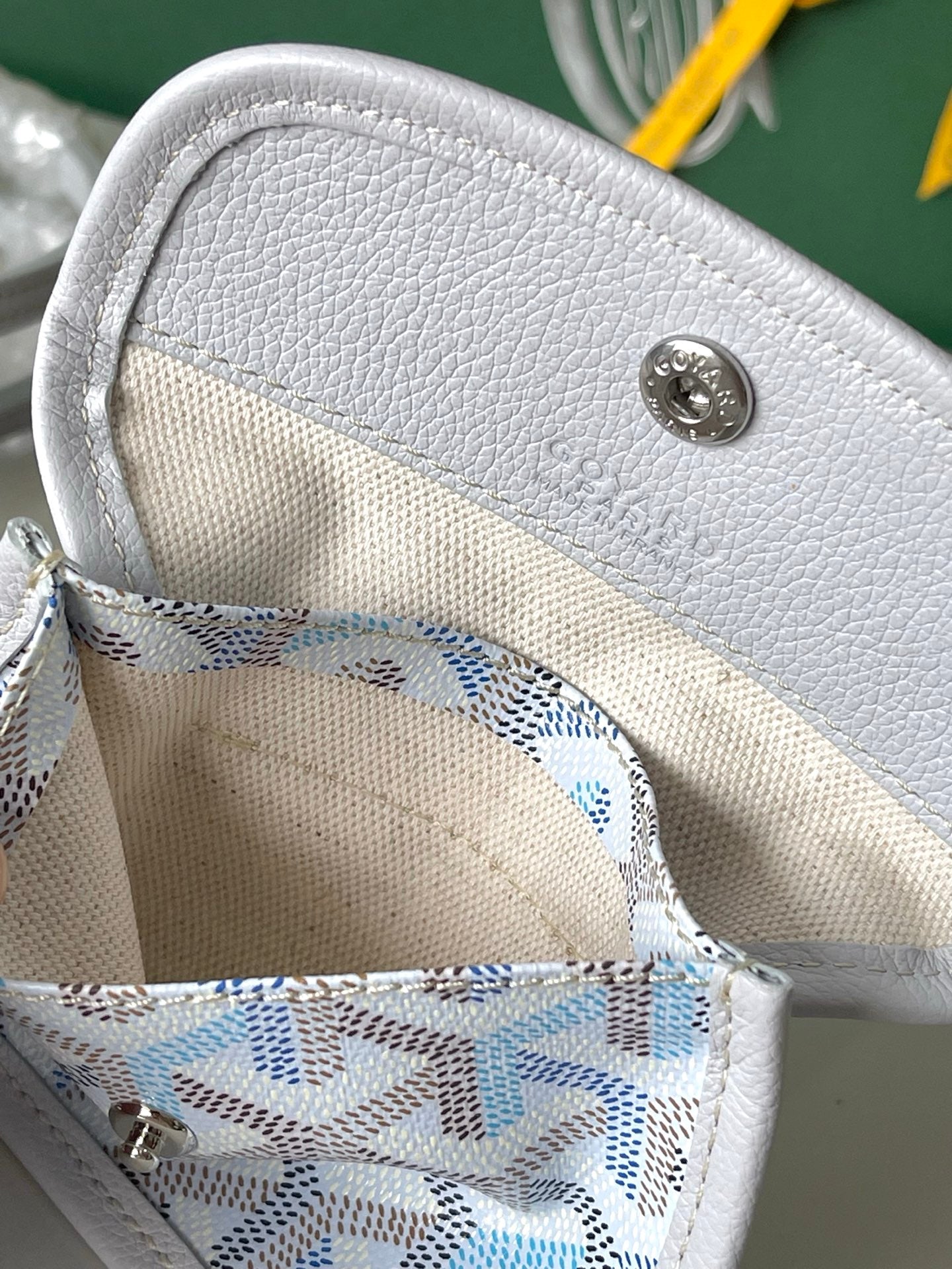 Interior pocket of light blue patterned tote with gray snap button and stitched lining