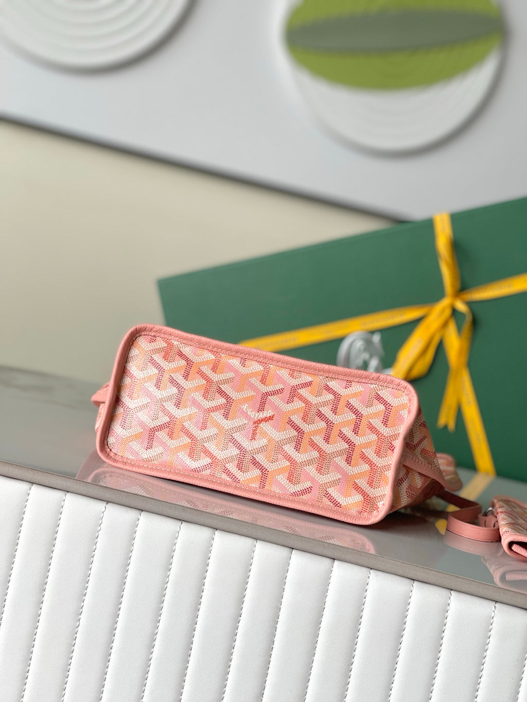 Pink patterned mini pouch with zip top and wrist strap, logo print design.