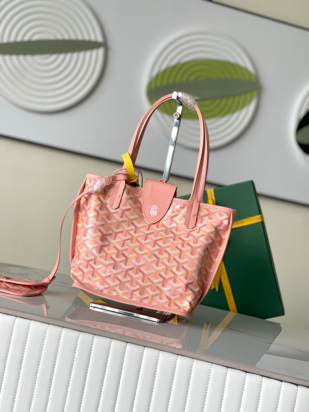 Pink patterned tote bag with top handles, side view, and small accessory at front.