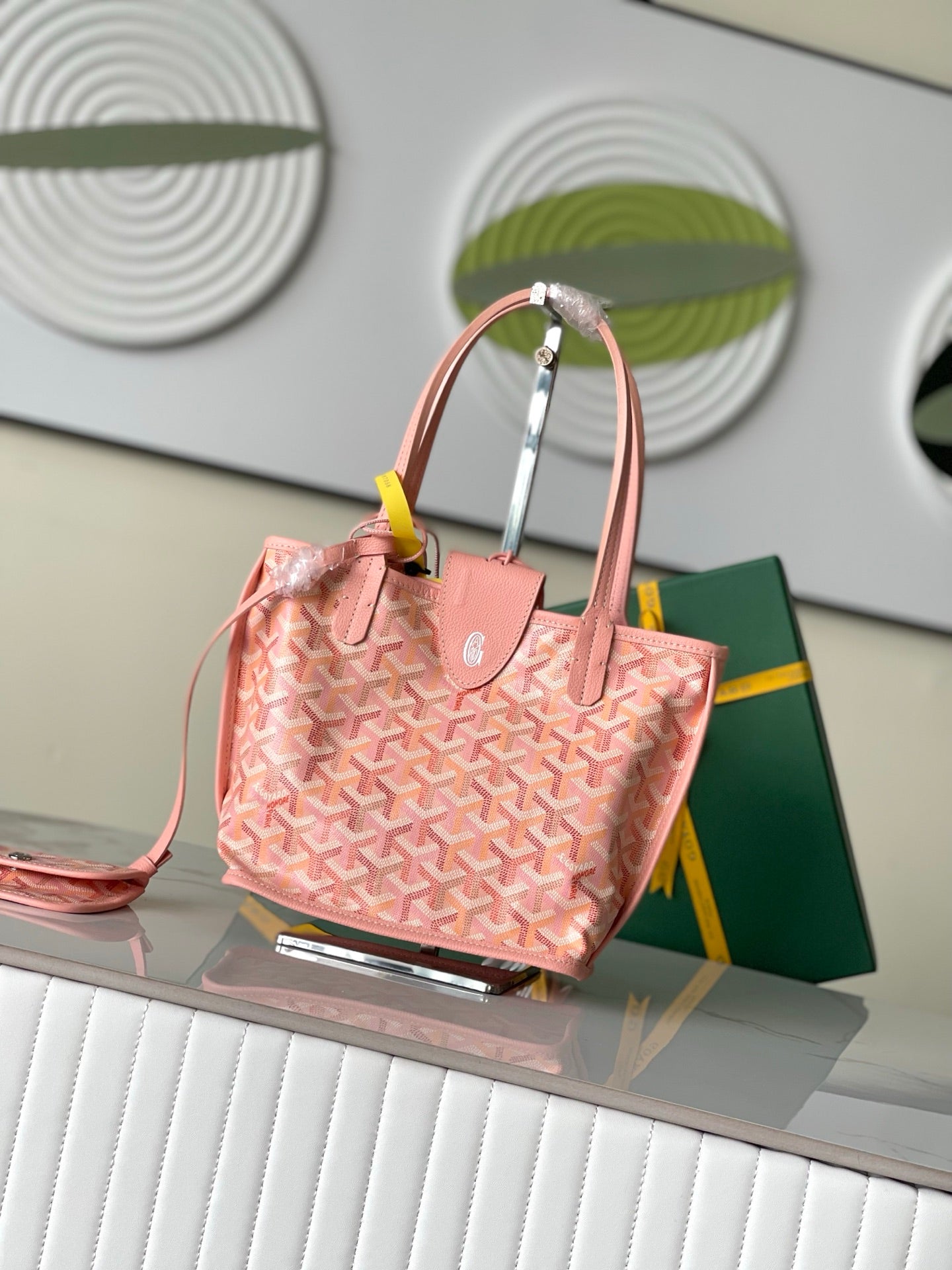 Pink patterned tote bag with top handles, side view, and small accessory at front.