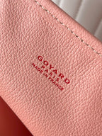Pink leather panel with embossed Goyard text logo and stitched seam detail.
