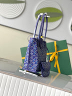 Goyard patterned tote bag with blue handles and hanging tag, angled view
