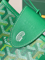 Green Goyard leather flap with metal emblem snap and stitched trim over patterned fabric