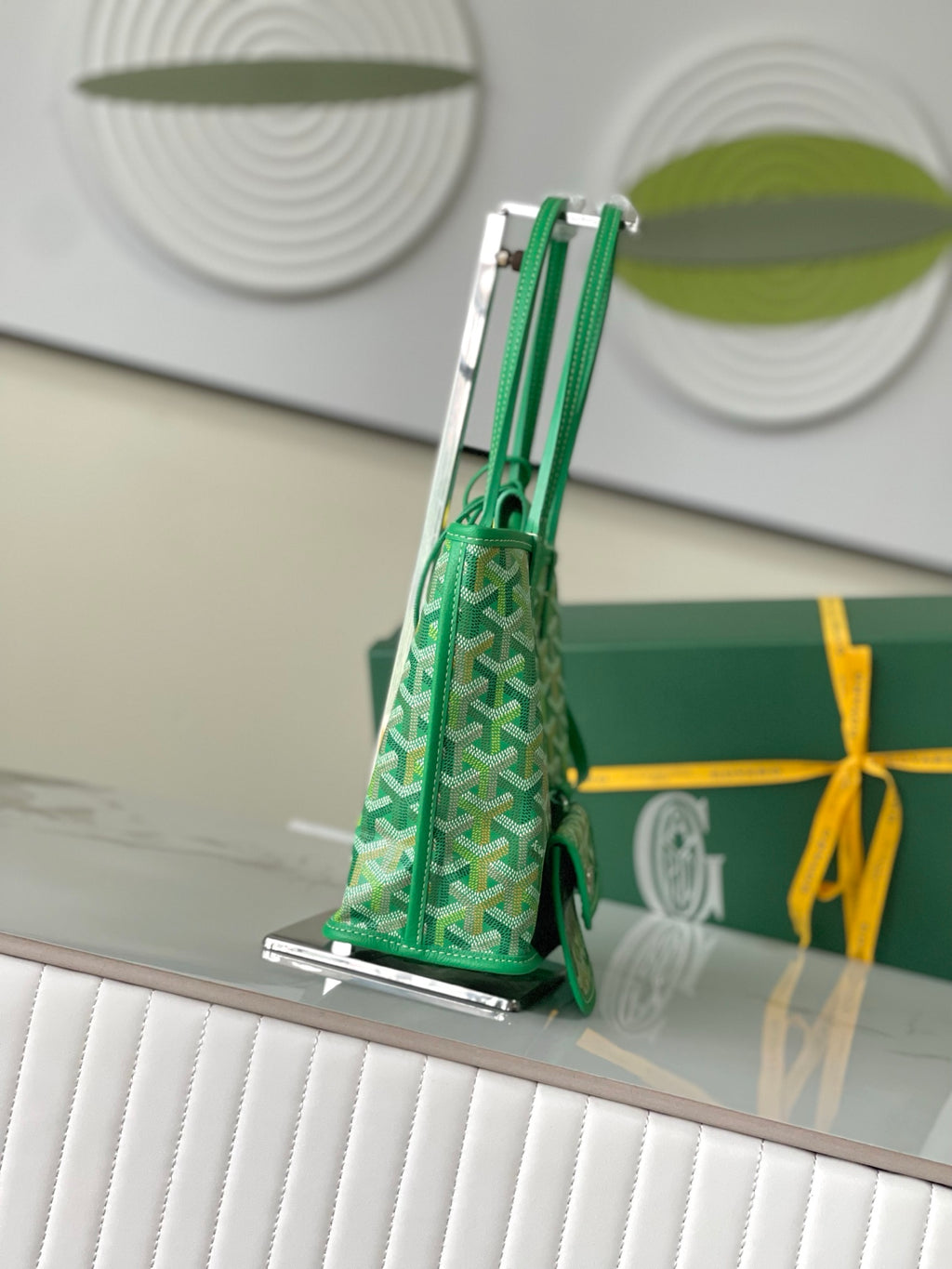 Green Goyard handbag viewed from side with structured shape, patterned canvas, and top handles
