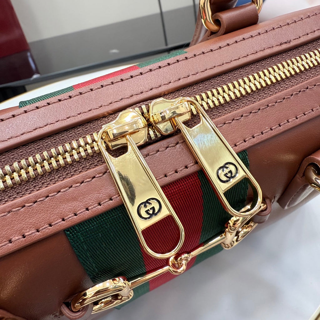 Brown leather bag with green-and-red stripe and gold zipper pull.