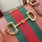 Brown leather bag detail with green-and-red web and gold double-link hardware.