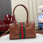 Brown leather handbag with green-and-red stripe, gold hardware, and hanging charm tag.