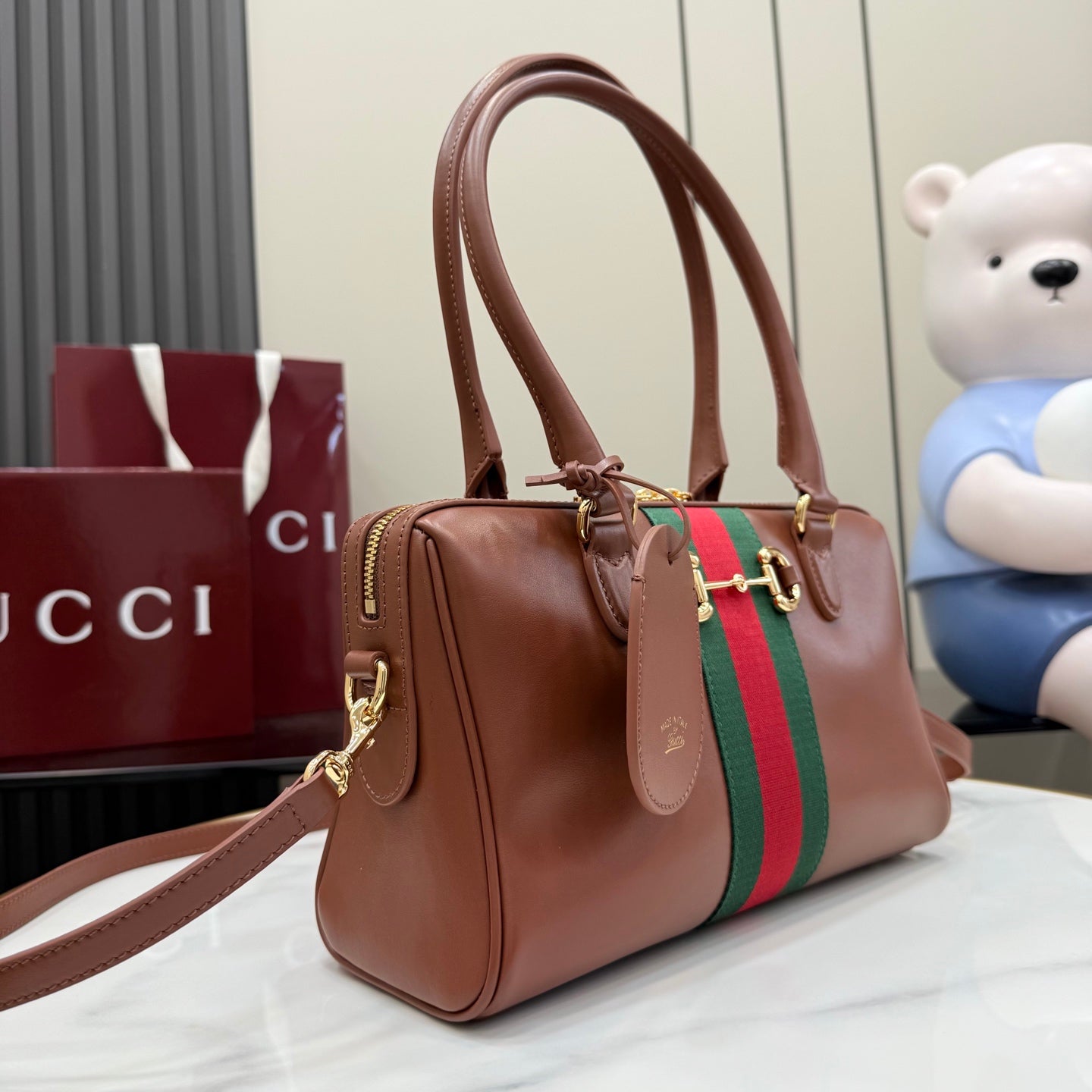Brown leather handbag with top handles, green/red web stripe, gold-tone hardware.