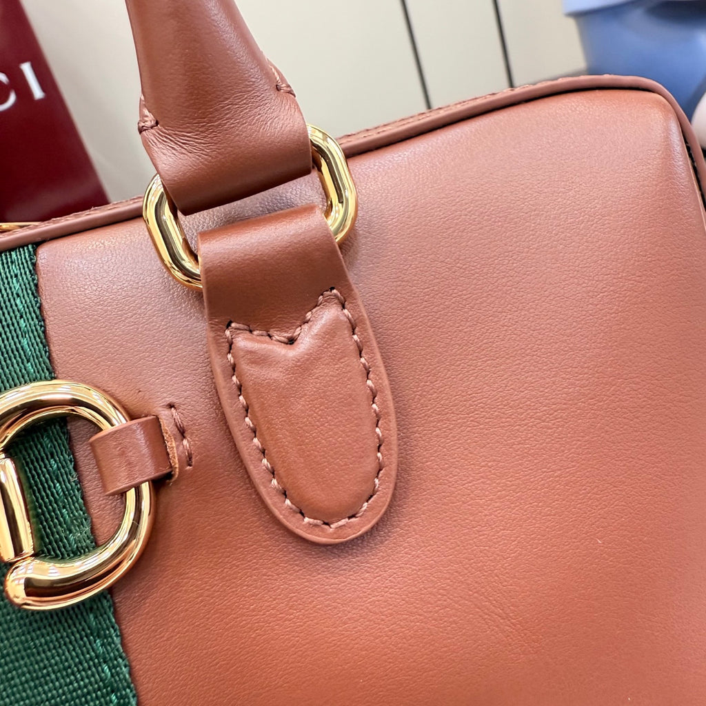Brown leather handbag with stitched leather tab and gold-tone ring hardware.