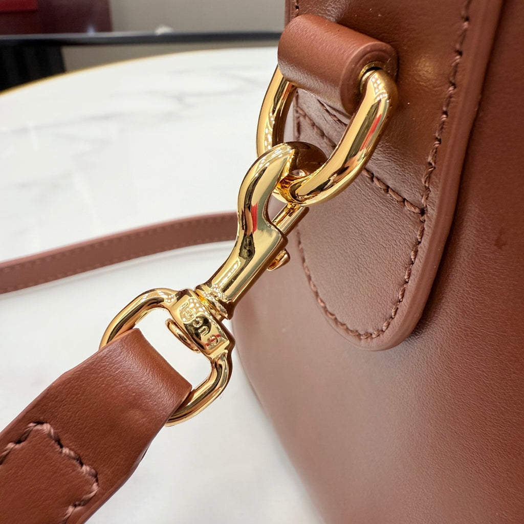 Brown leather bag with gold-tone ring clasp and stitched trim.