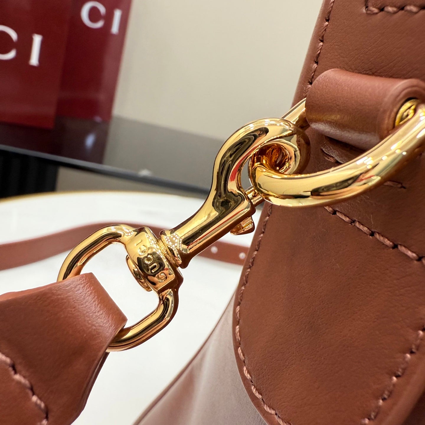 Gucci tote bag close-up of gold-tone clasp hardware on brown leather strap