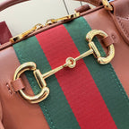 Gucci tote bag close-up: gold-tone double G hardware with green-red web stripe