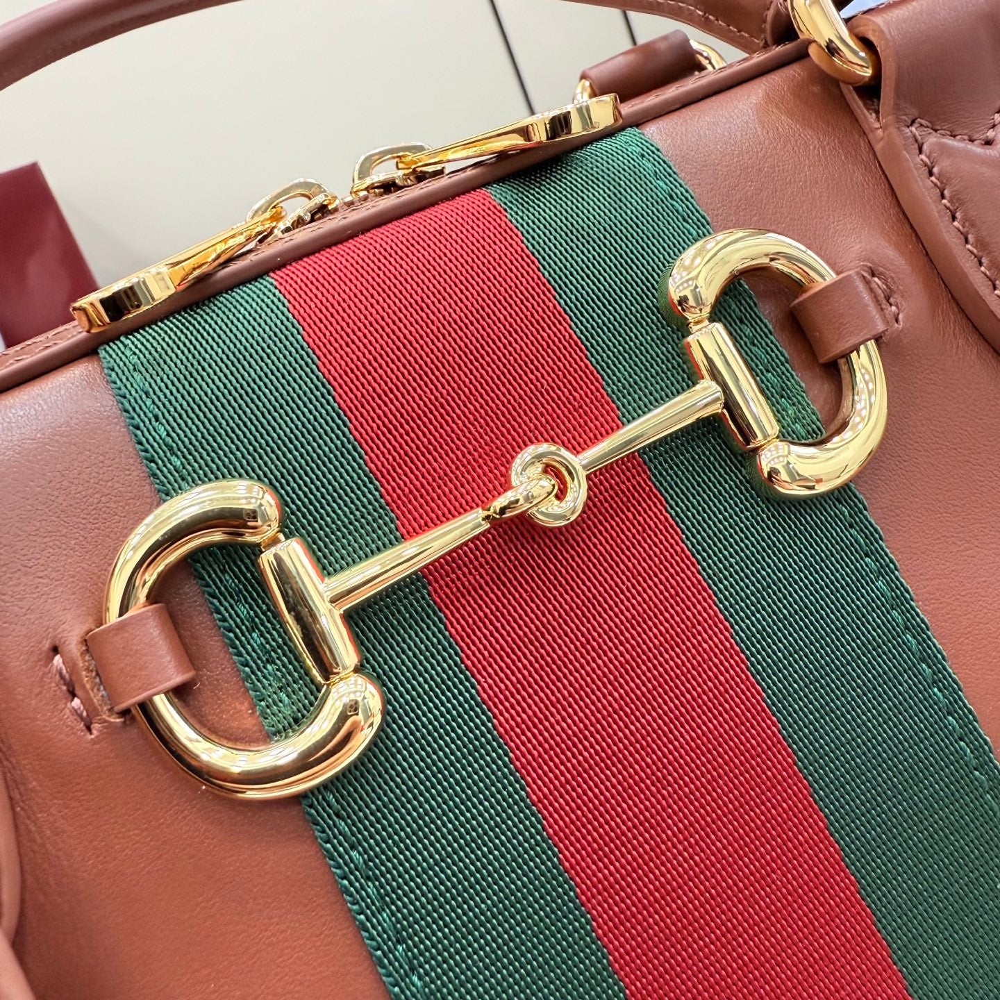 Gucci tote bag close-up: gold-tone double G hardware with green-red web stripe