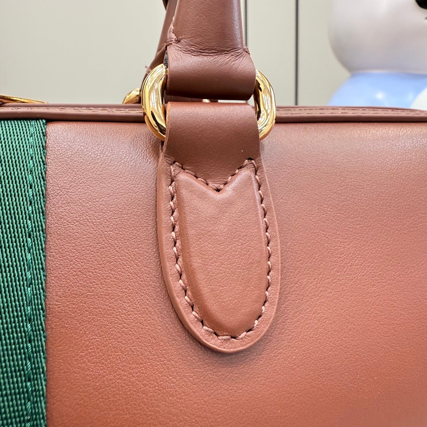 Gucci bag front strap tab with gold ring hardware and stitched detail