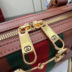 Gucci tote bag close-up: gold zipper pull and green-red web stripe with brown trim