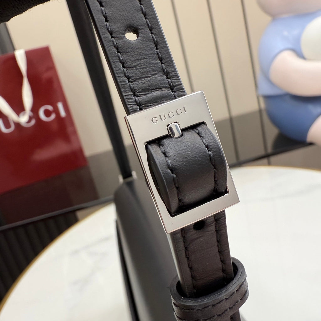 Black leather bag strap with Gucci logo metal buckle and stitched attachment tab