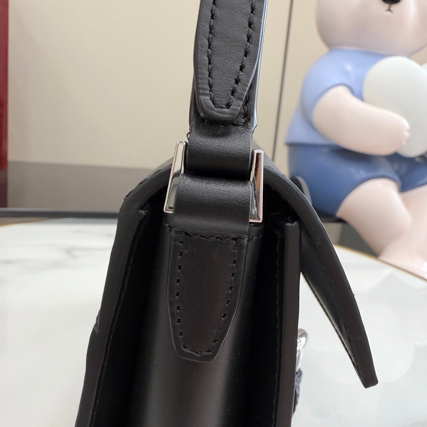 Black leather top-handle section with stitched handle loops and silver-tone connector hardware