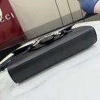 Black leather bag with long strap and silver-tone hardware on top flap, angled close-up