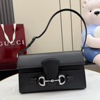 Black leather shoulder bag with flap, silver-tone horsebit clasp, and curved top handle