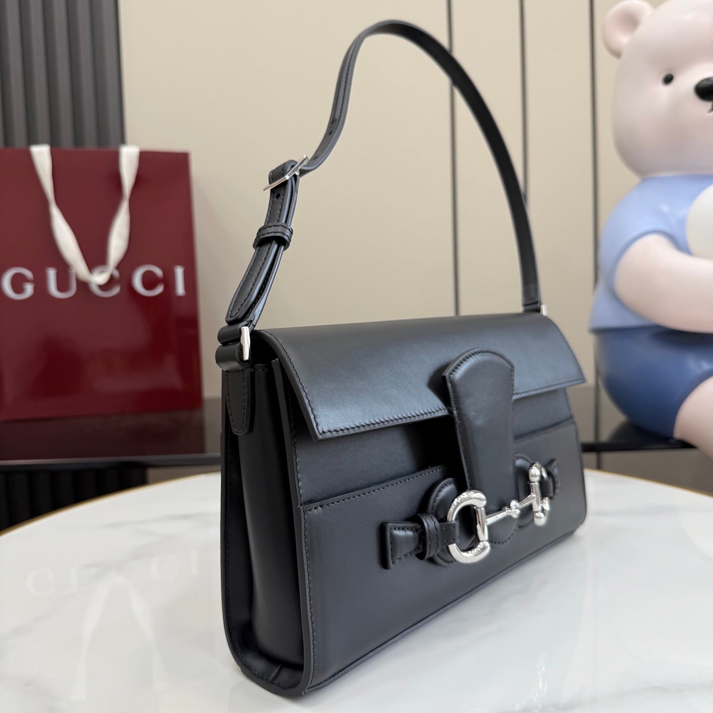 Black leather shoulder bag with flap, curved handle, and silver-tone horsebit clasp