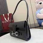 Black leather shoulder bag with flap and silver-tone horsebit front hardware, side view