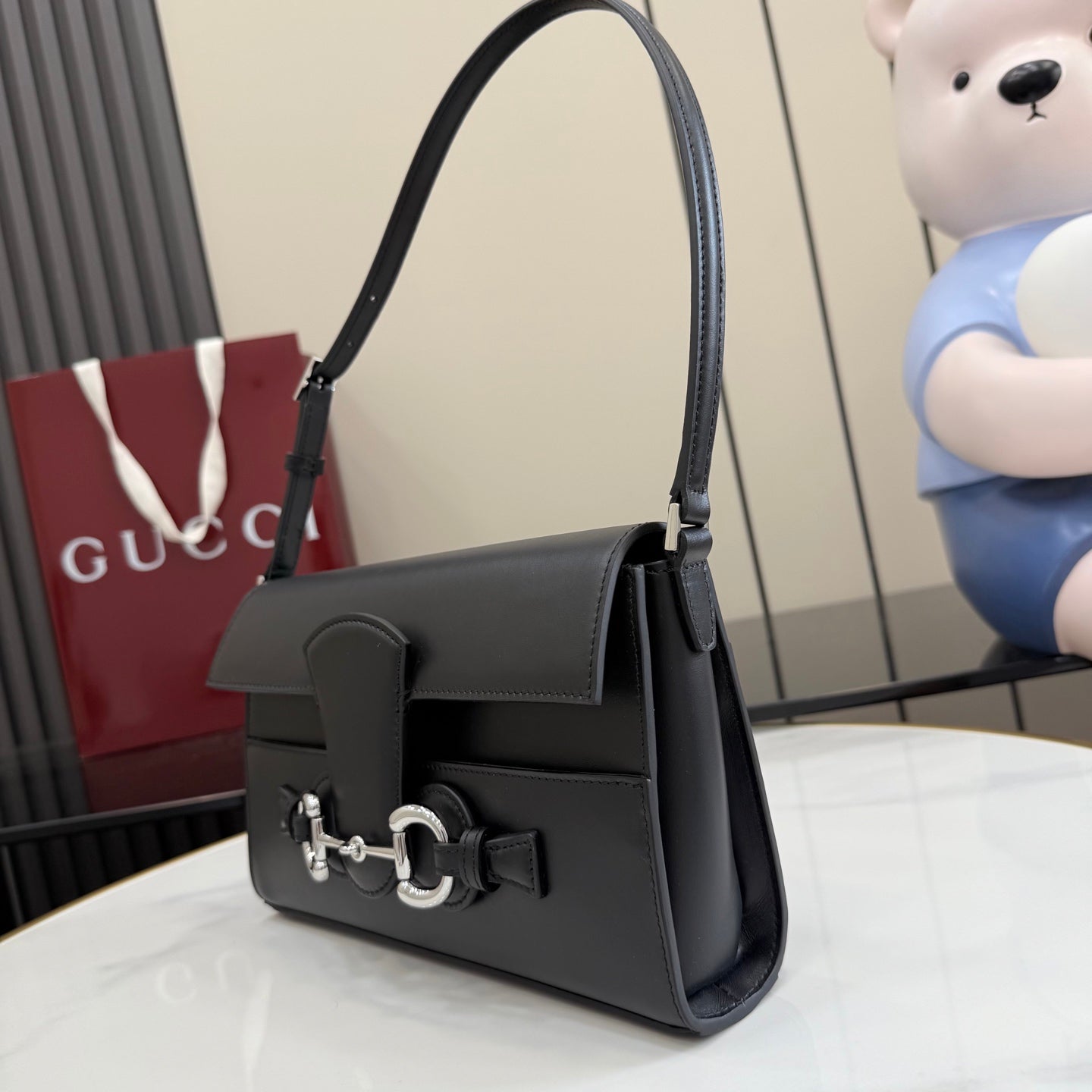 Black leather shoulder bag with flap and silver-tone horsebit front hardware, side view