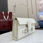 Cream top-handle shoulder bag with flap closure, front strap hardware, and curved handle