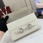 Cream handbag with flap closure, front metal clasp, and optional shoulder strap opening