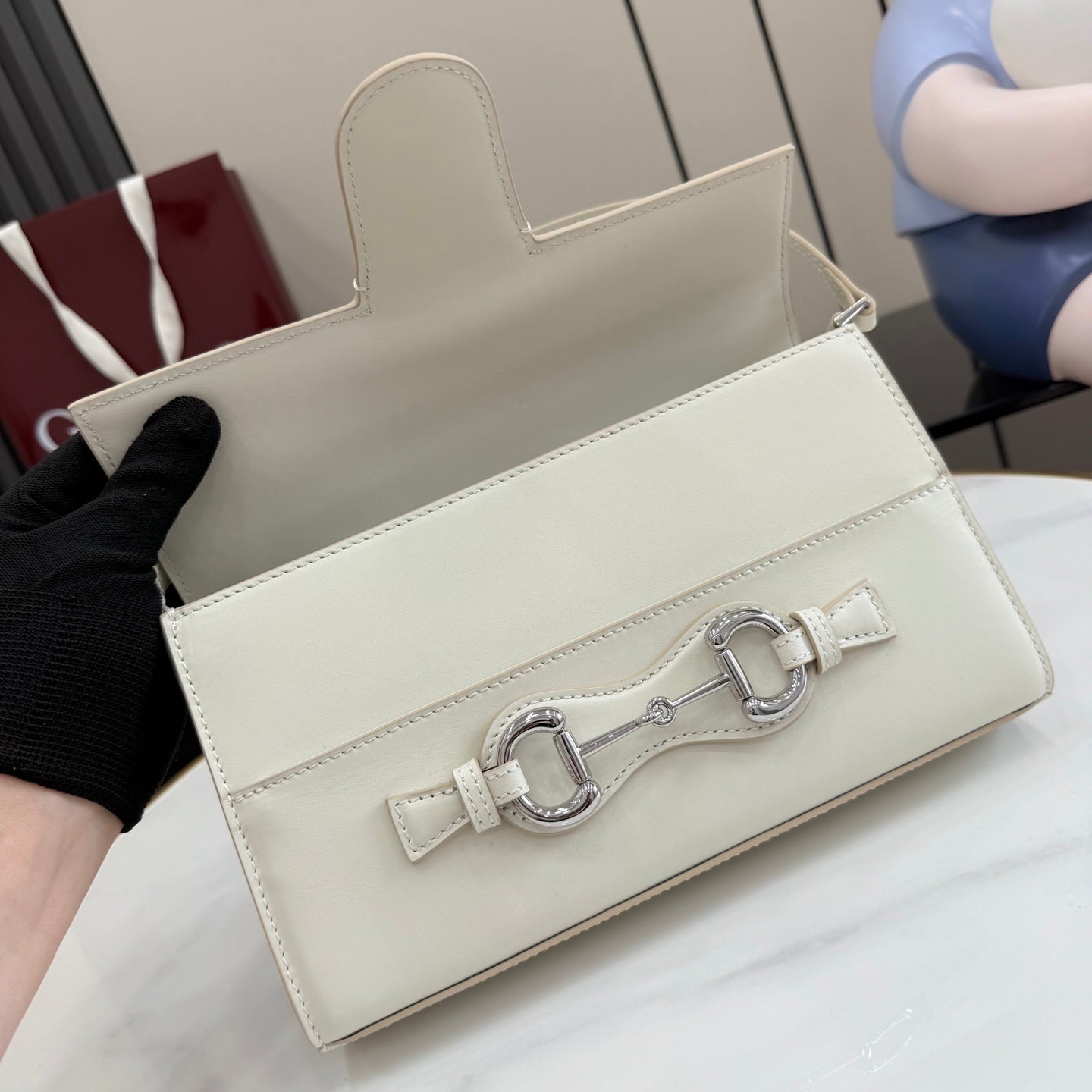 Cream handbag with flap closure, front metal clasp, and optional shoulder strap opening