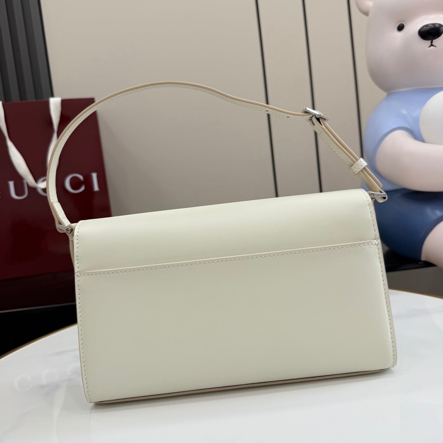 Cream rectangular shoulder bag with long top handle and smooth front flap