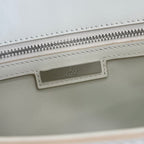 Cream bag with stitched label and silver zipper on the top edge