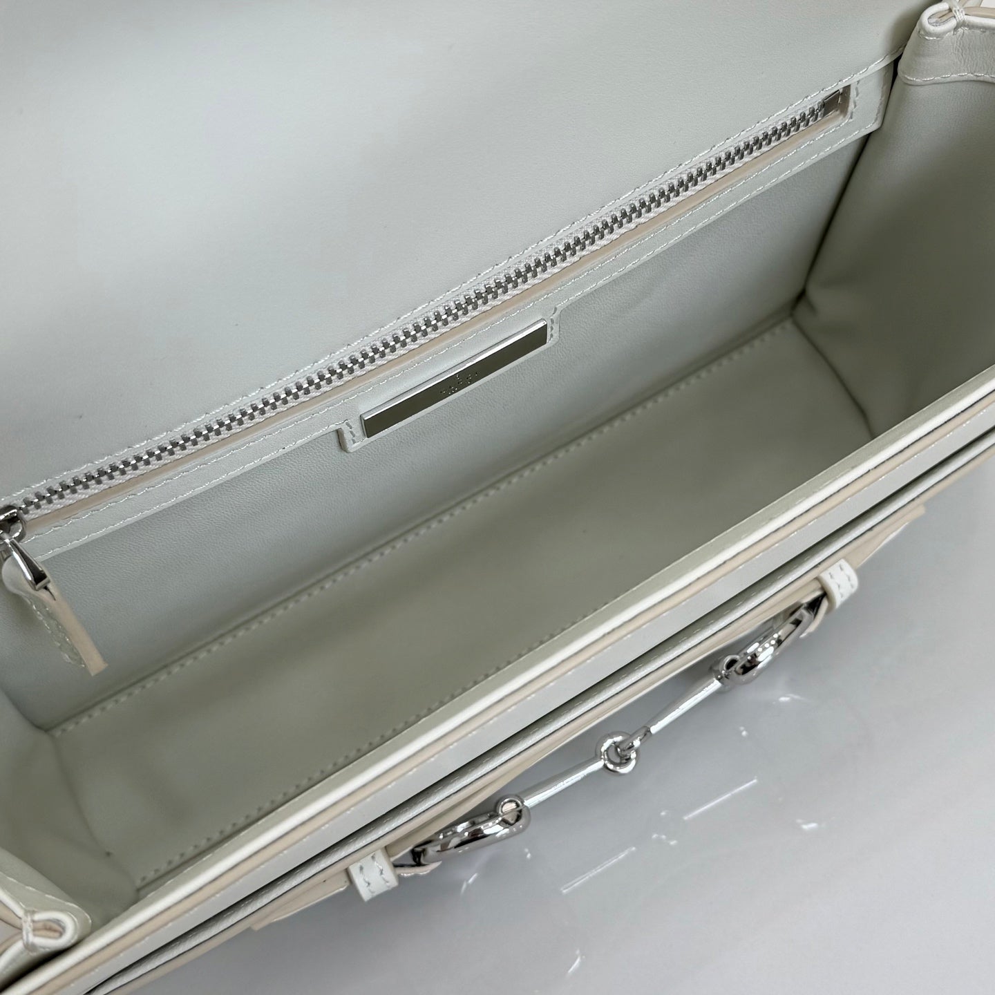 Cream bag interior view with zippered top edge, lining, and inner metal zipper pull