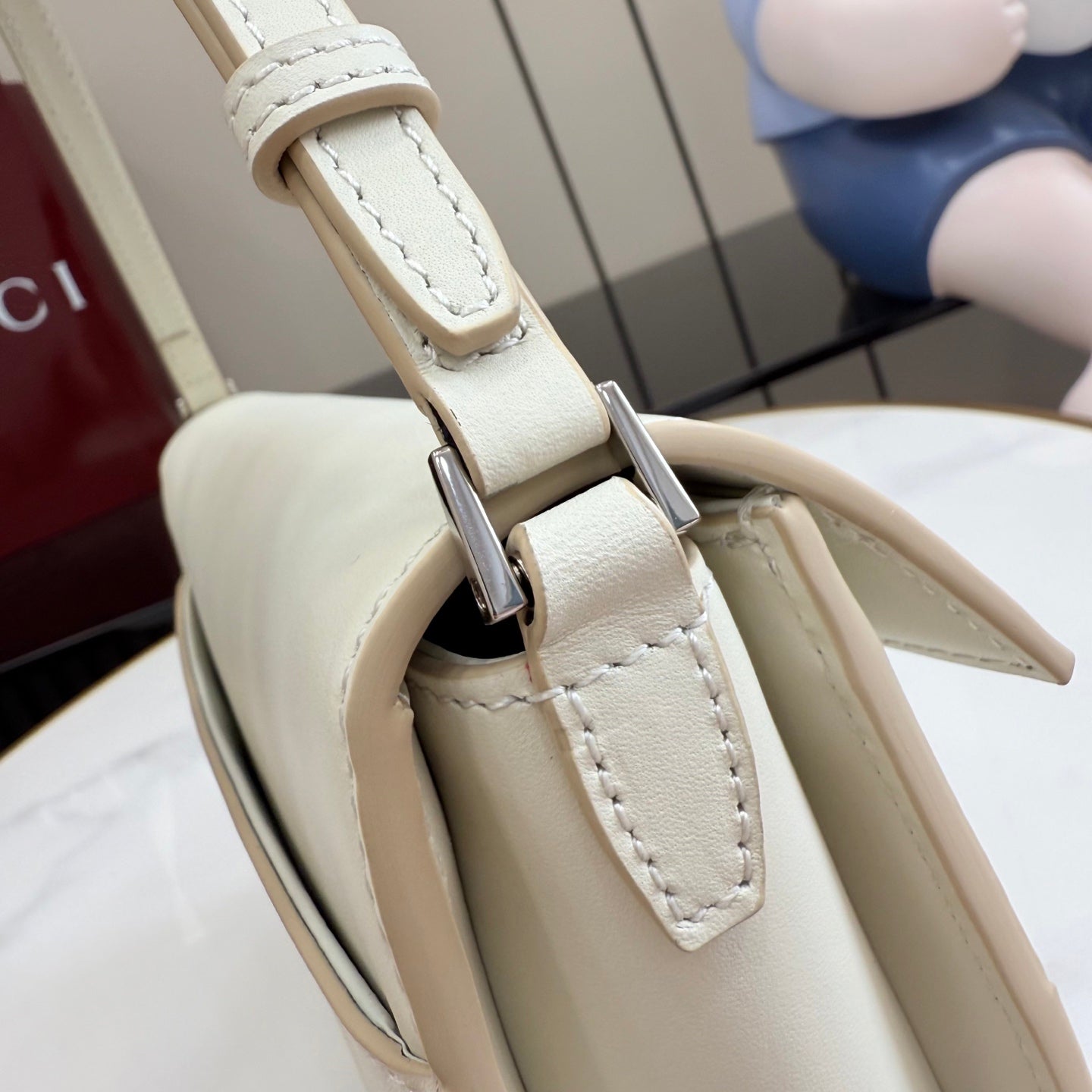 Cream bag strap hardware and stitched panel with metal swivel clasp attachment