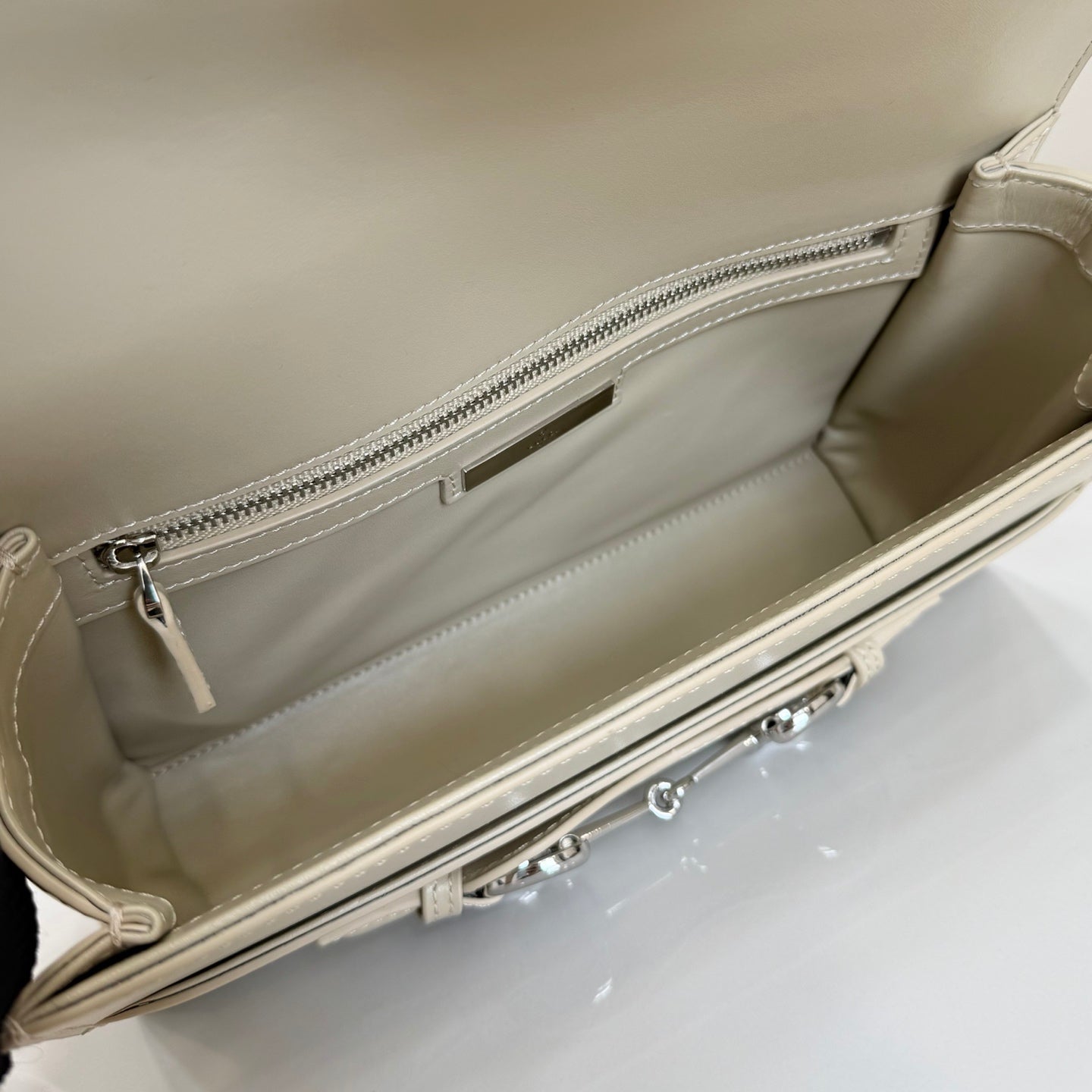 Gucci mini bag interior in light beige with zippered pocket and silver zipper.