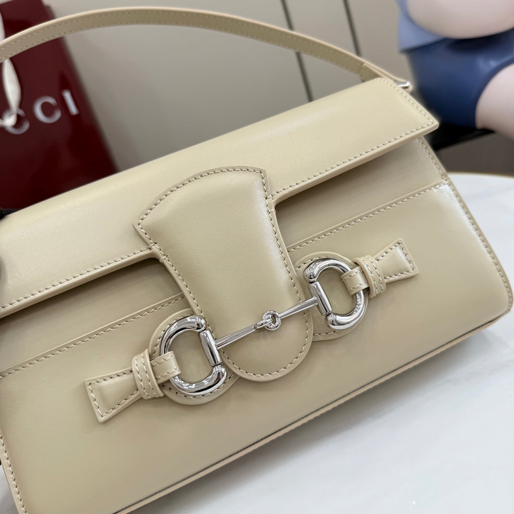 Gucci mini bag front detail in light beige with metal bar buckle and leather tab.