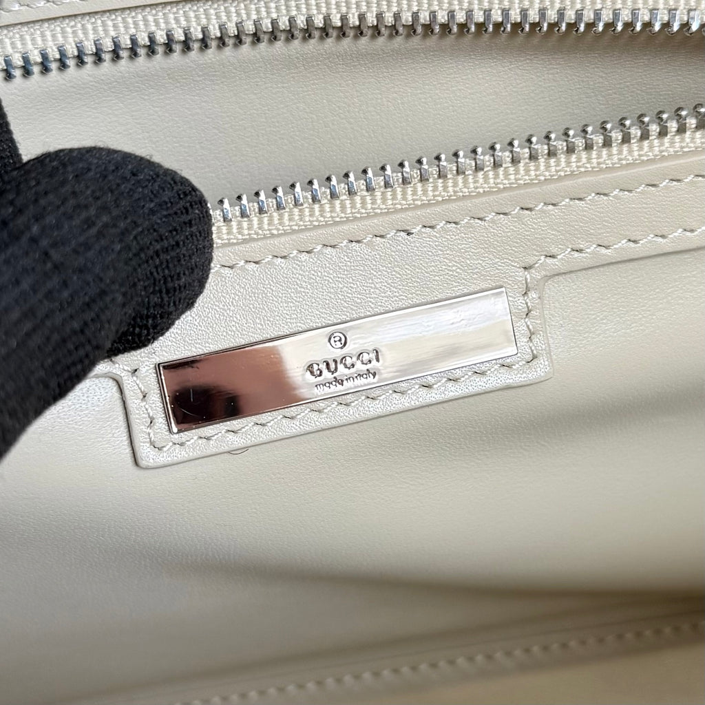 Gucci mini bag inside view with Gucci leather patch and silver zipper track.