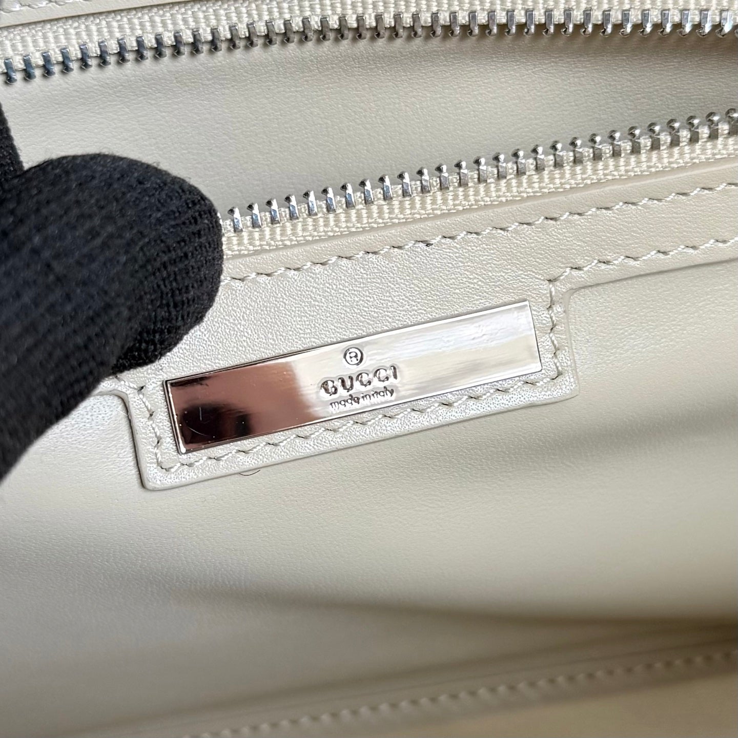 Gucci mini bag inside view with Gucci leather patch and silver zipper track.