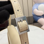 Gucci bag strap close-up in light beige with metal buckle and Gucci logo plate.