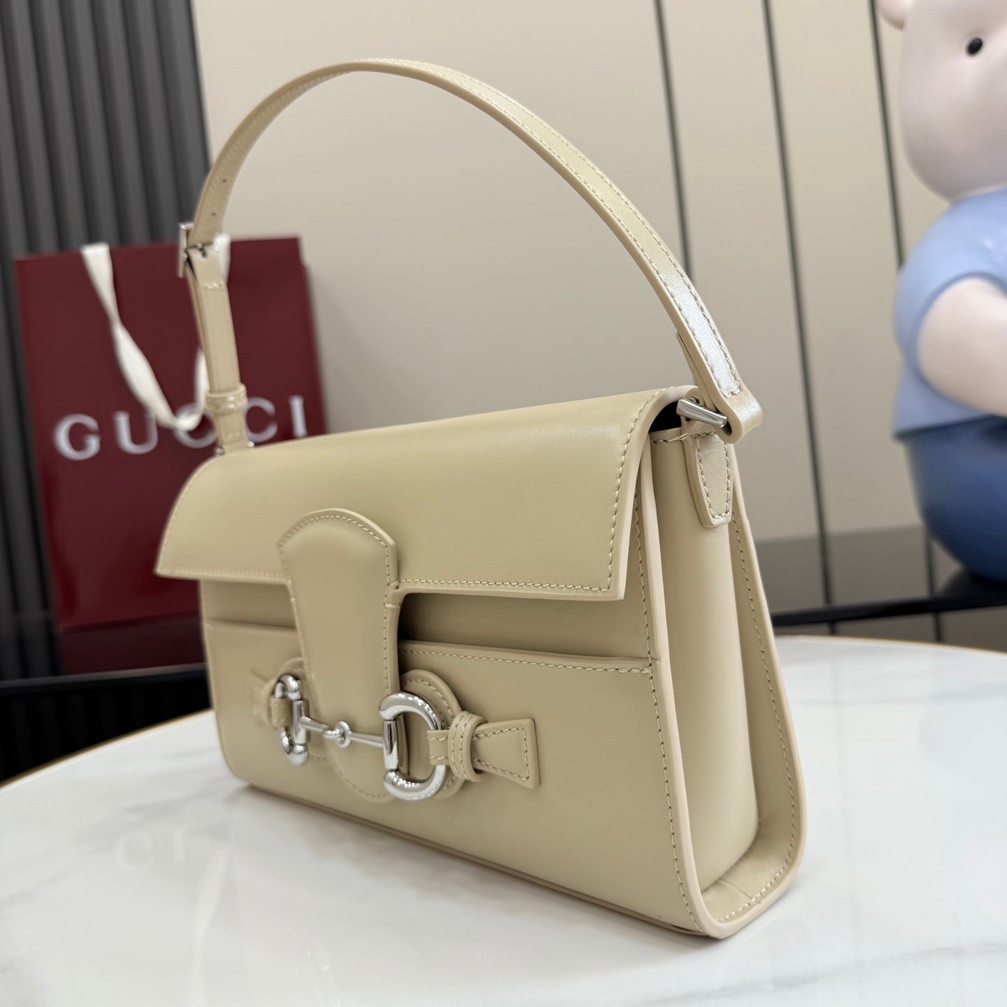 Gucci mini bag in light beige with shoulder strap and flap with metal clasp.