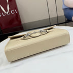 Gucci mini bag in light beige, underside view with strap hardware and stitching.