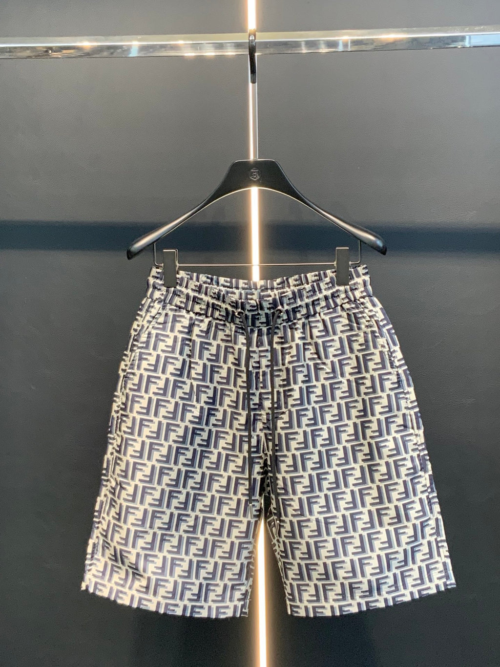 Dior logo-pattern shorts on hanger, navy and white, straight silhouette.