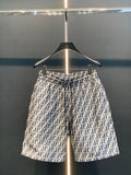 Dior logo-pattern shorts on hanger, navy and white, straight silhouette.