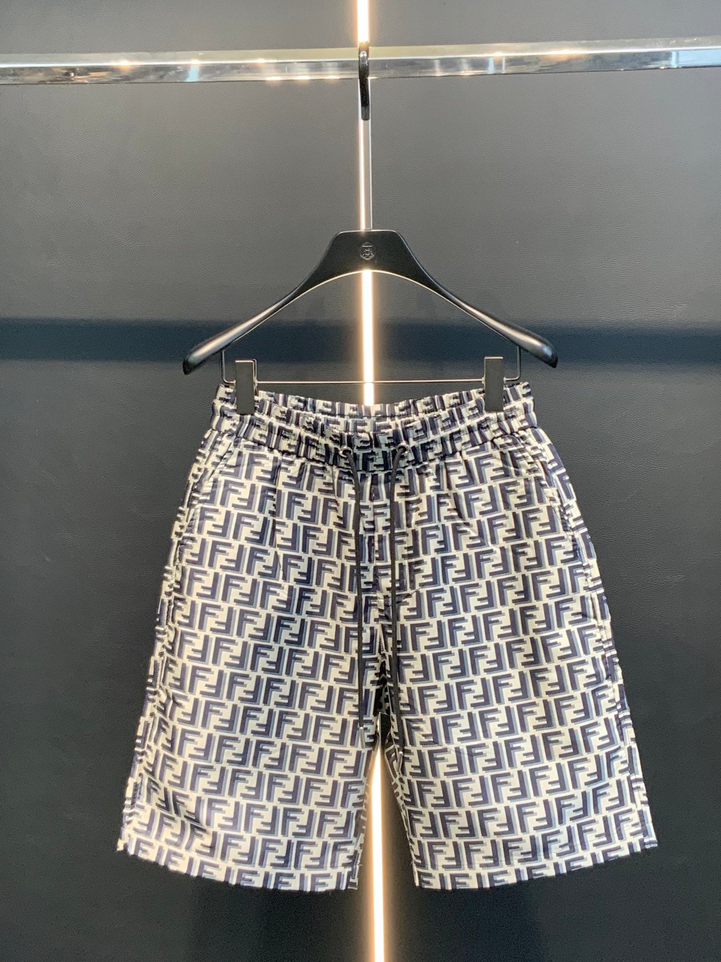 Dior logo-pattern shorts on hanger, navy and white, straight silhouette.