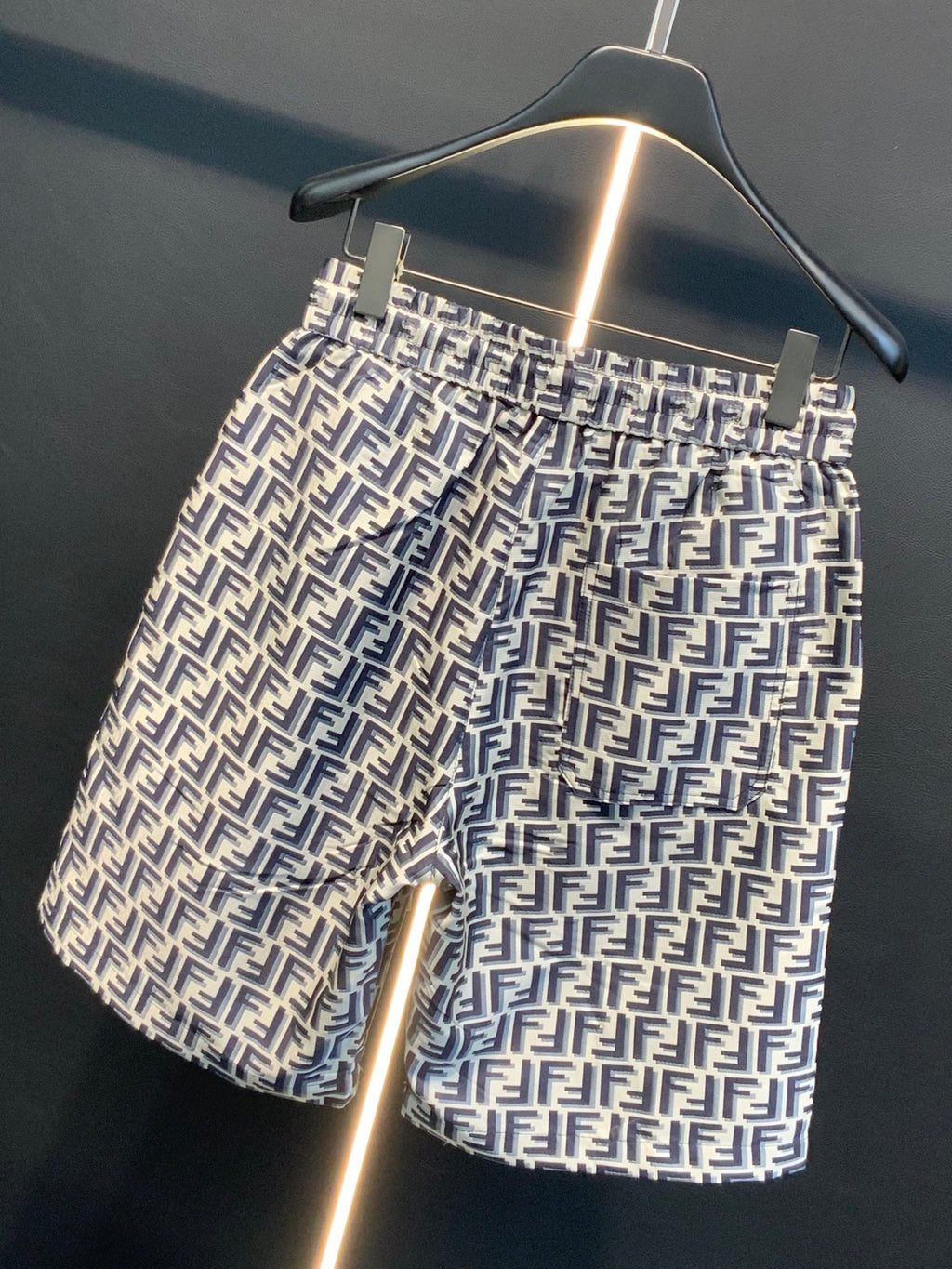 Dior logo-pattern shorts on hanger, side view showing pocket and side seam.