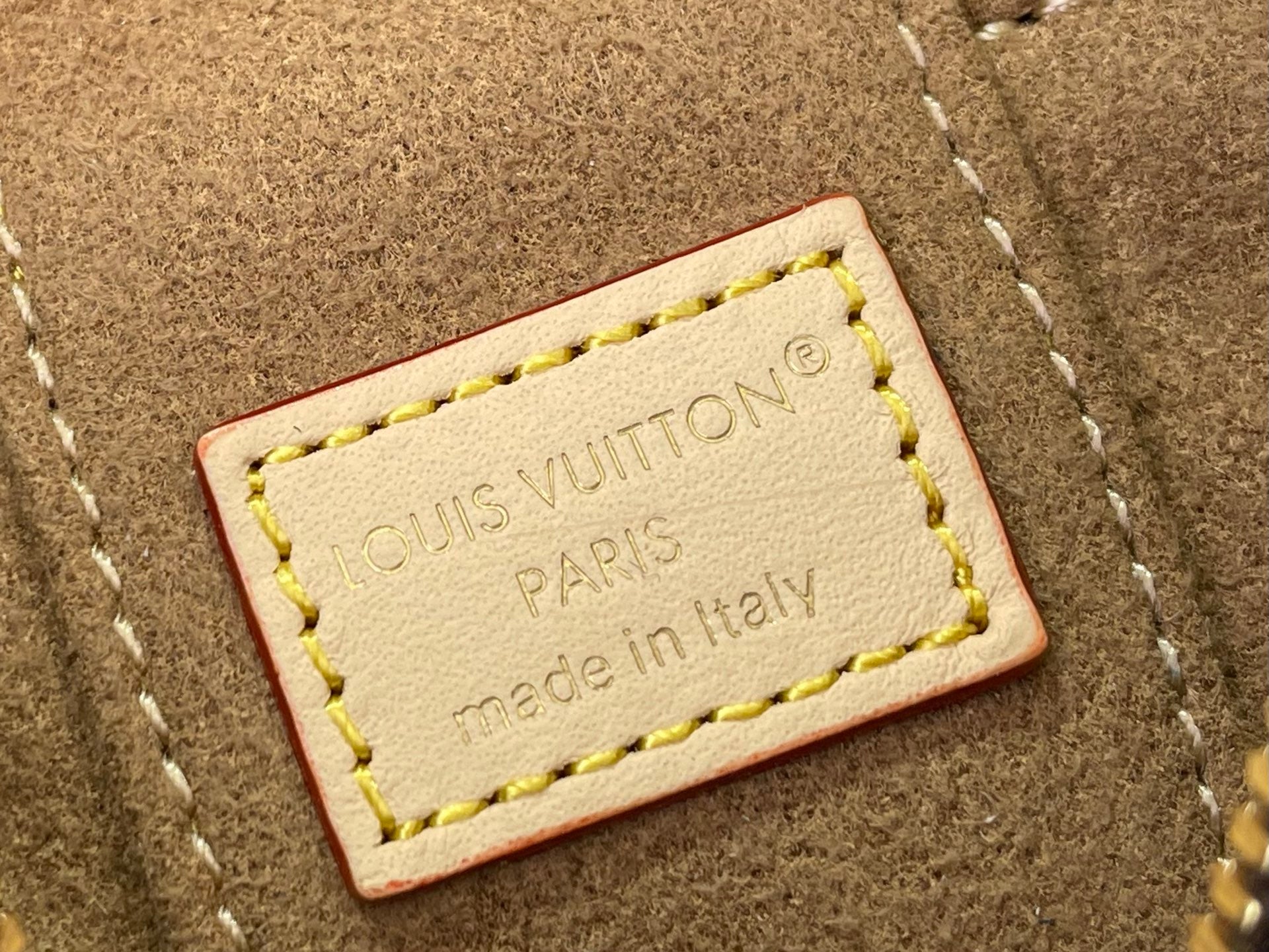 Leather brand tag on monogram bag reading Louis Vuitton Paris Made in Italy