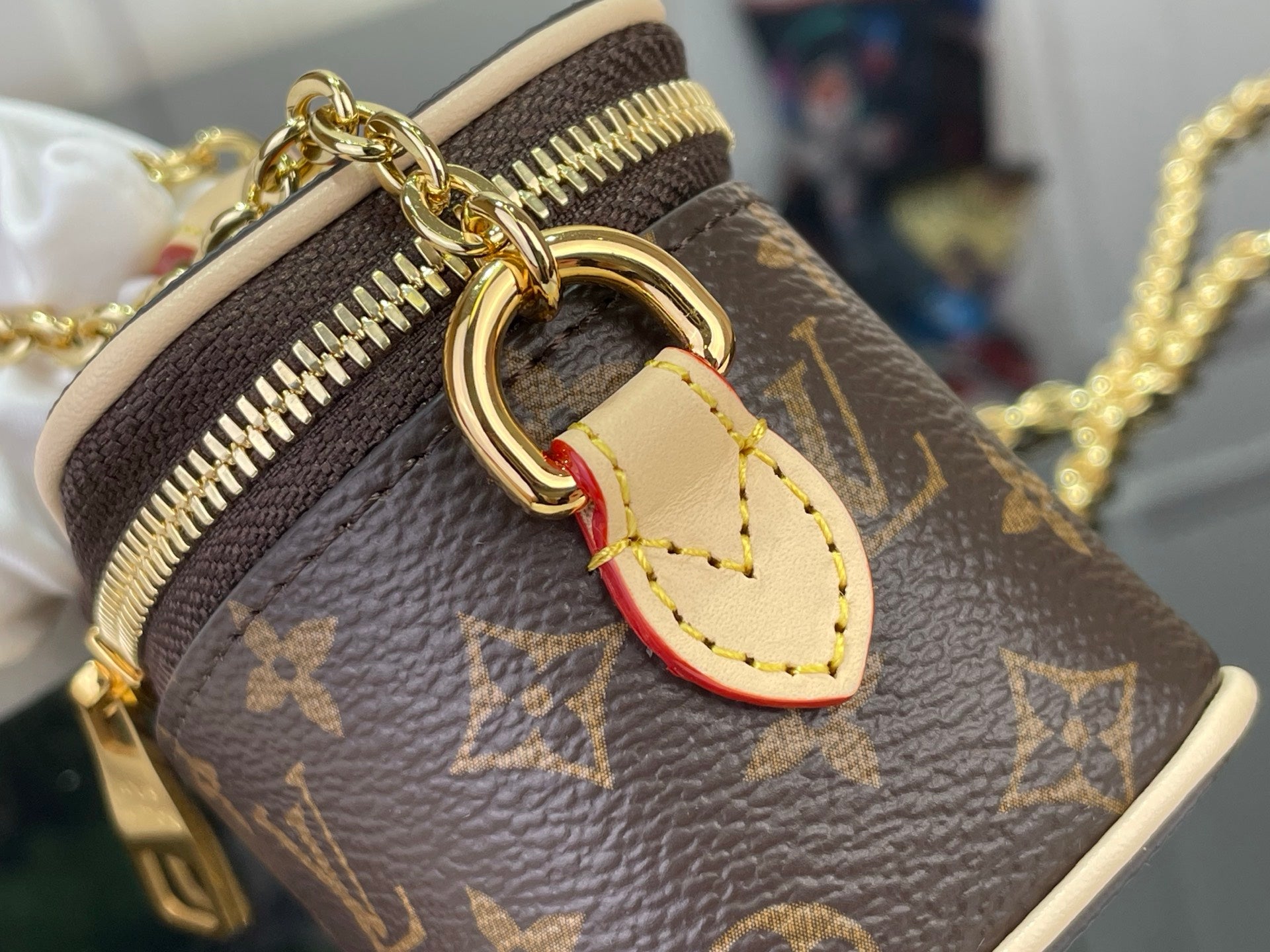 Monogram bag with gold clasp and small heart charm on brown canvas