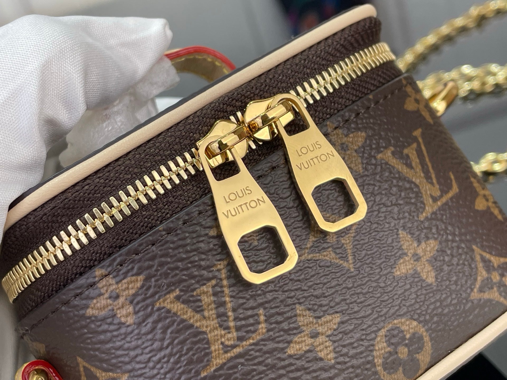 Monogram bag close-up: gold zipper and LV hardware plates on brown canvas