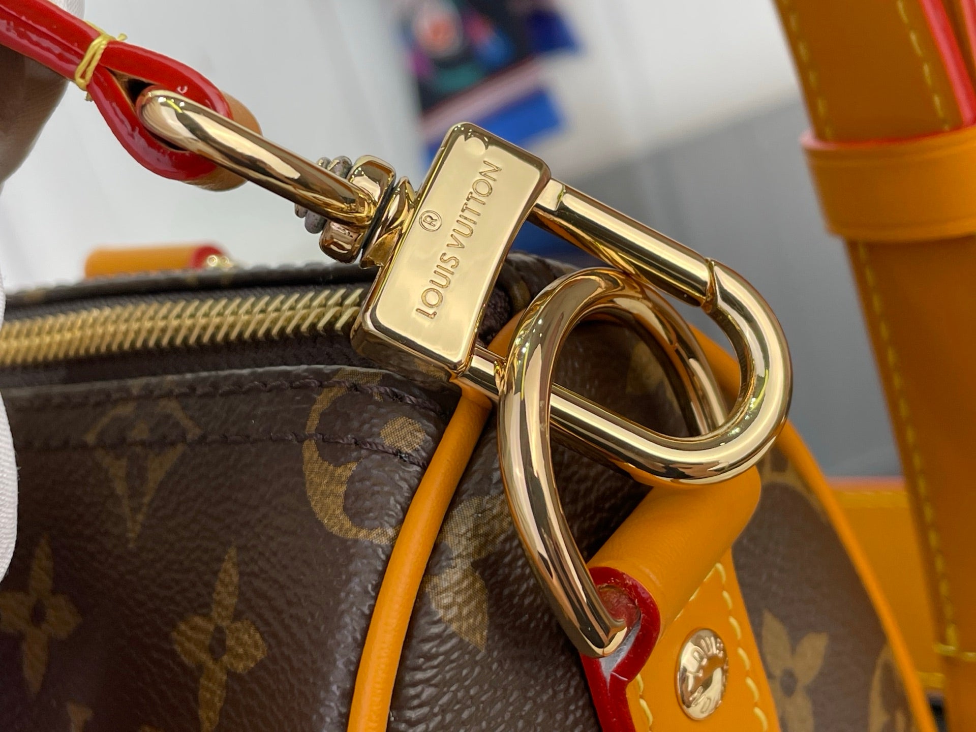 Louis Vuitton monogram bag clasp hardware with gold ring and orange strap